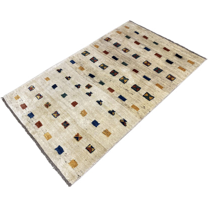Gabbeh rug angled view: beige background with colorful diamond and stripe patterns