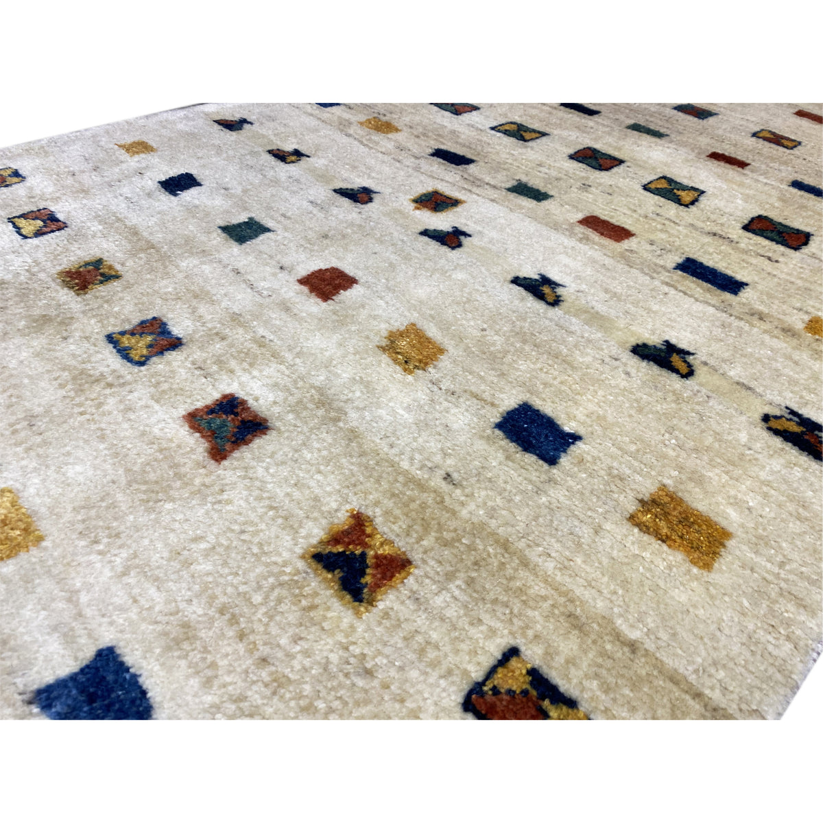 Close-up of the Gabbeh rug: beige pile with small multicolored motifs