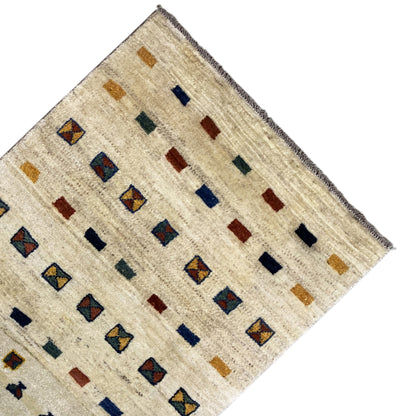 Corner of a Gabbeh rug: beige background with square patterns in blue and ochre