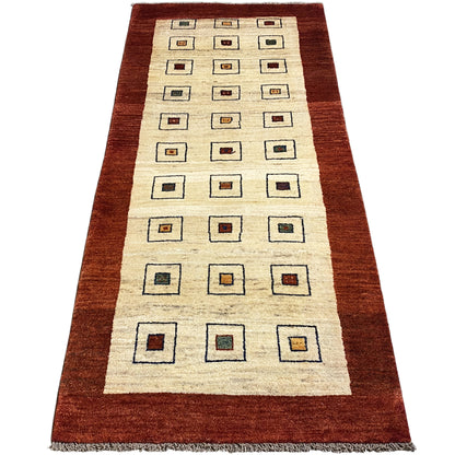 Runner rug with a cream-colored base and square motifs, brown border