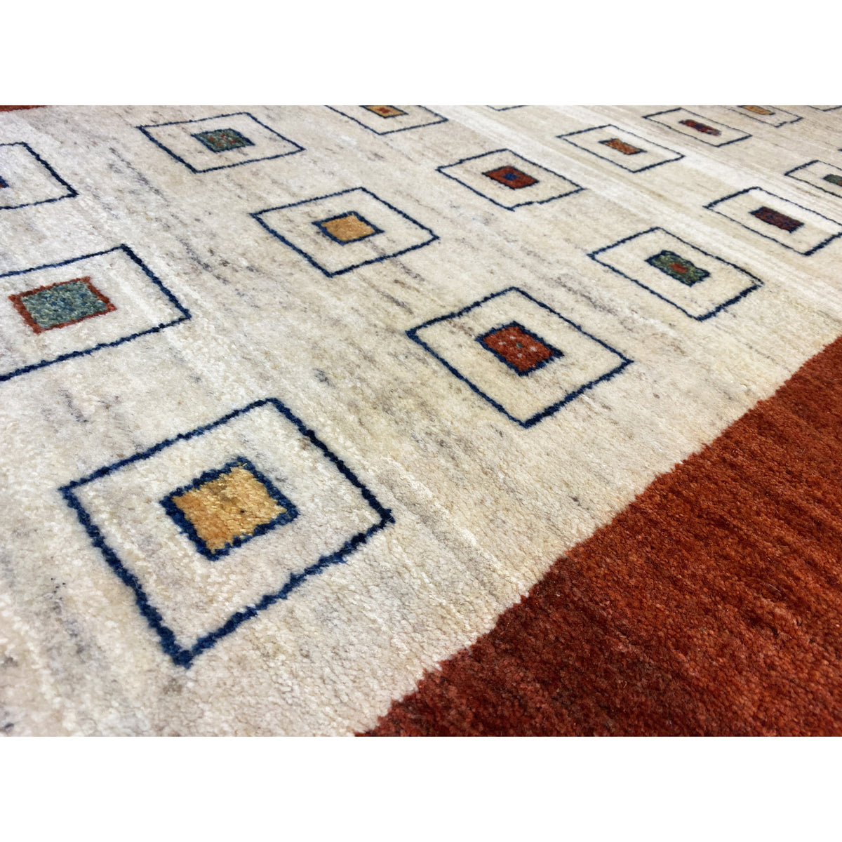 Runner rug detail: cream-colored pile with square motifs, brown border