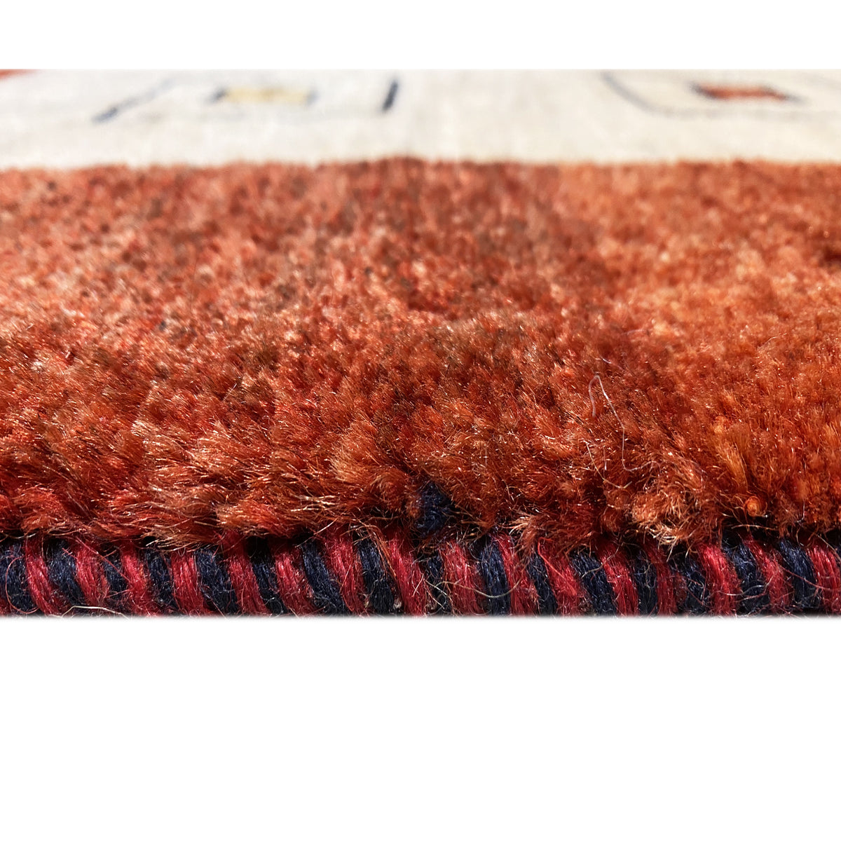 Runner rug pile and fringe view: reddish-brown fabric with a dark border