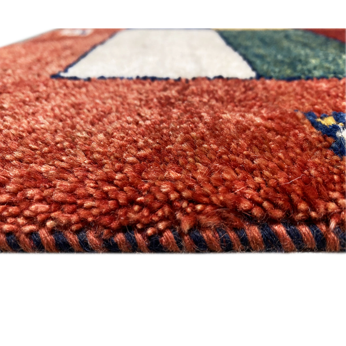 Carpet surface of the Gabbeh runner: red, densely woven pile structure with a patchwork background