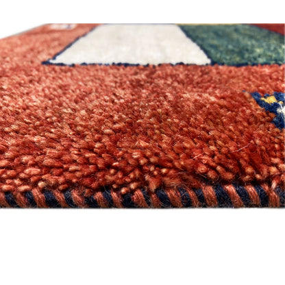 Carpet surface of the Gabbeh runner: red, densely woven pile structure with a patchwork background