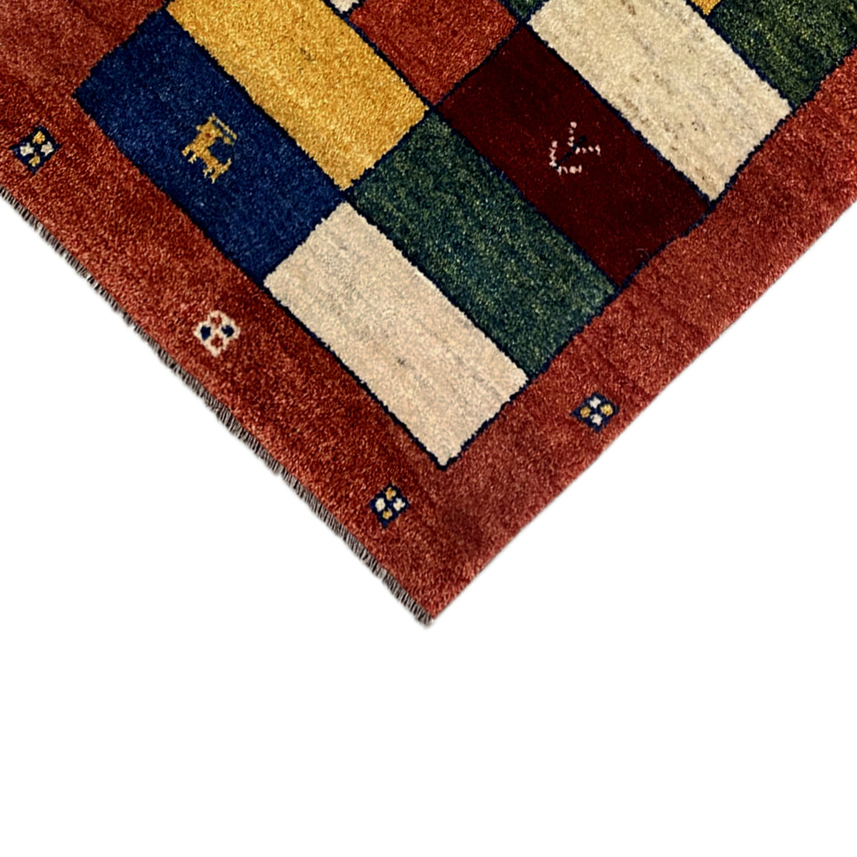 Gabbeh runner detail: border and patchwork sections in reddish brown, cream, blue, and green
