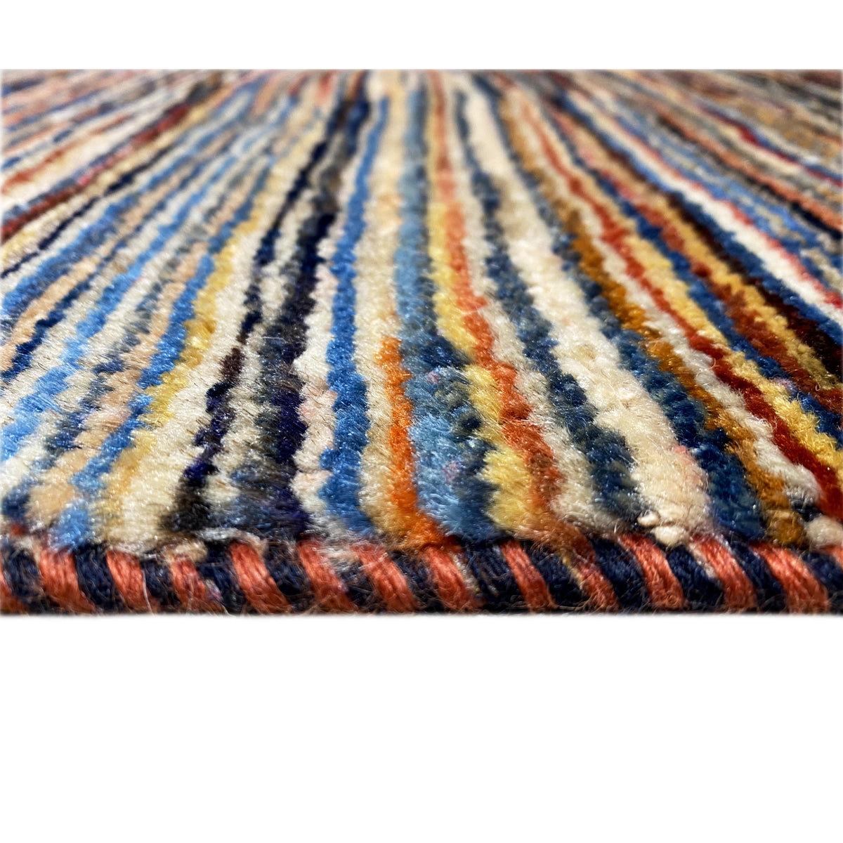 Close-up of a Gabbeh rug: blue and beige stripes with orange accents
