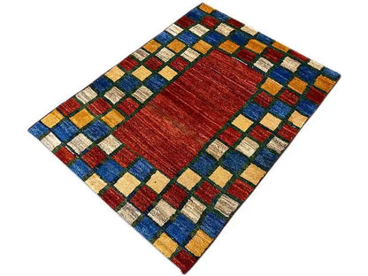 Rug, diagonal view: red center and colorful square patterns around the edge