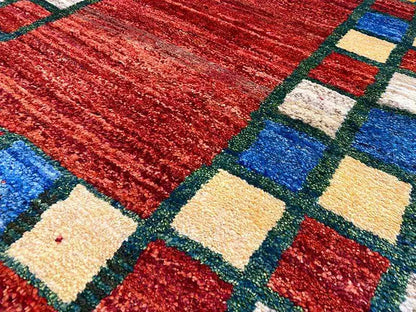 Carpet detail: red area with square patterns in blue, yellow, and beige