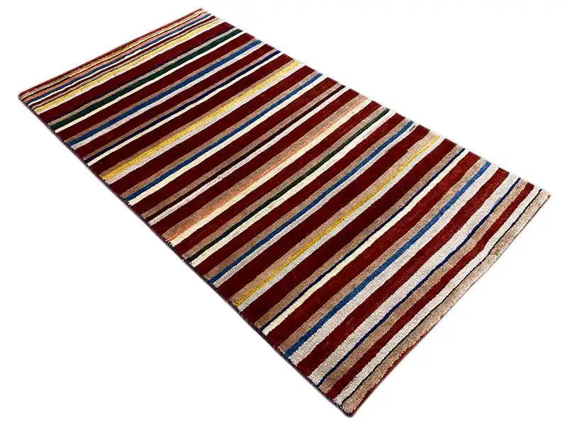 Rug, diagonal striped design in shades of brown, cream, blue, and yellow