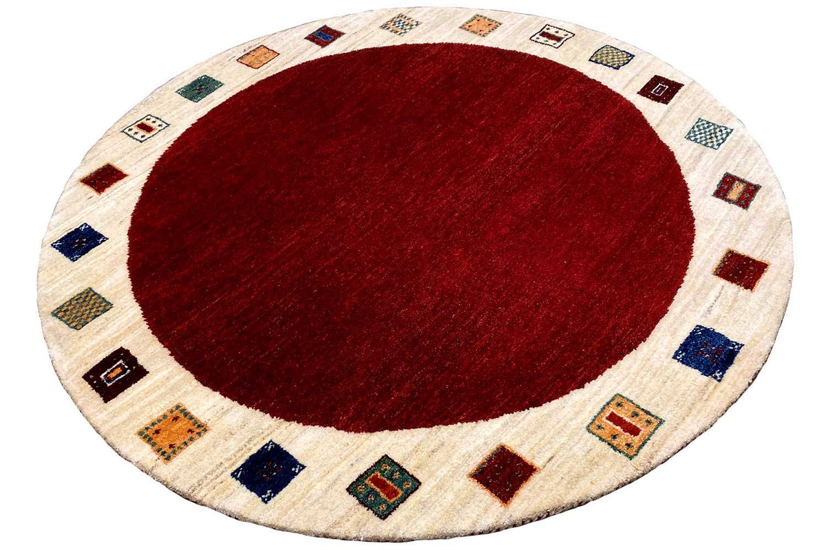 Round Gabbeh rug, red circular pattern in the center, cream-colored border with squares