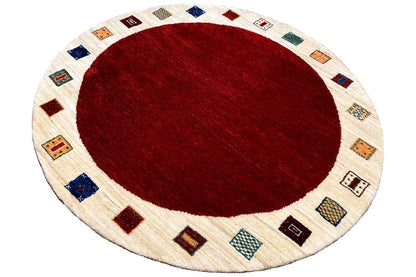 Round Gabbeh rug with a red inner circle and a cream-colored ring made of small shapes