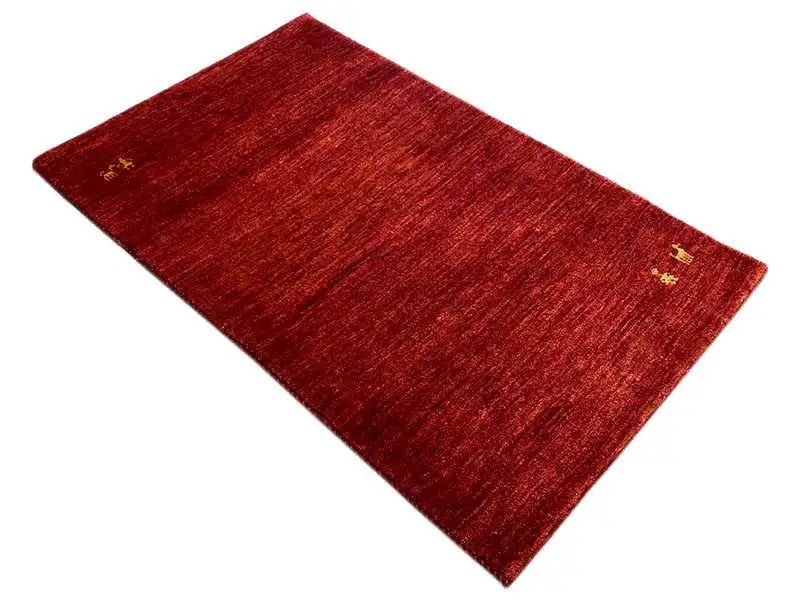 Red Gabbeh rug with a fine woven pattern and yellow accents, laid at an angle