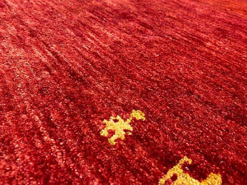 Close-up of a red Gabbeh rug with yellow medallion motifs in a fine pile
