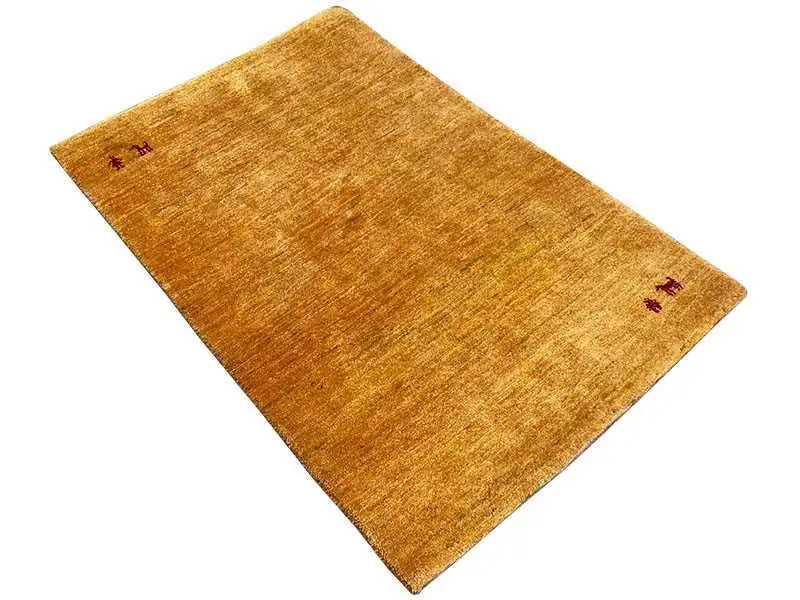 Mustard-yellow Gabbeh rug with small red animal motifs, photographed diagonally