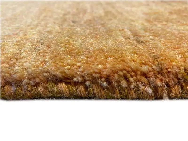 Close-up of a Gabbeh rug: mustard-yellow pile with a dense, textured surface