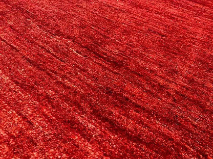 Gabbeh rug, close-up of the surface: mottled red with a fine, grainy texture