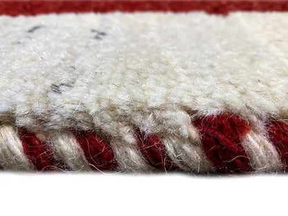 Gabbeh rug, close-up: pile fibers from cream and reddish areas with fringes