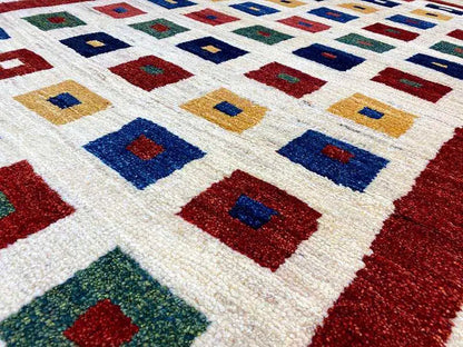 Gabbeh rug, pattern detail: square motifs in blue, red, and green on a light background