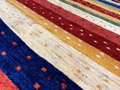 Gabbeh rug detail with stripes in blue, red, cream, and gold