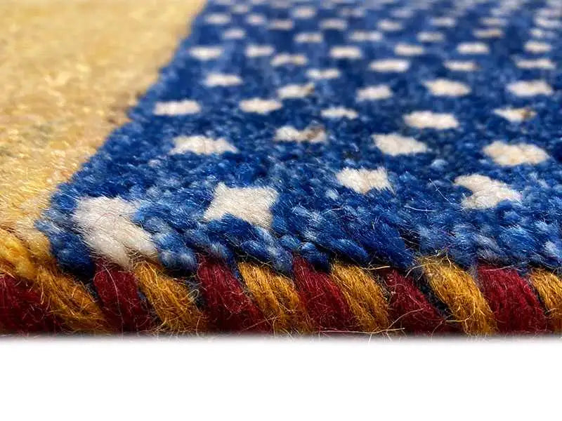 Gabbeh rug detail: blue pattern with white dots and colored border stripes