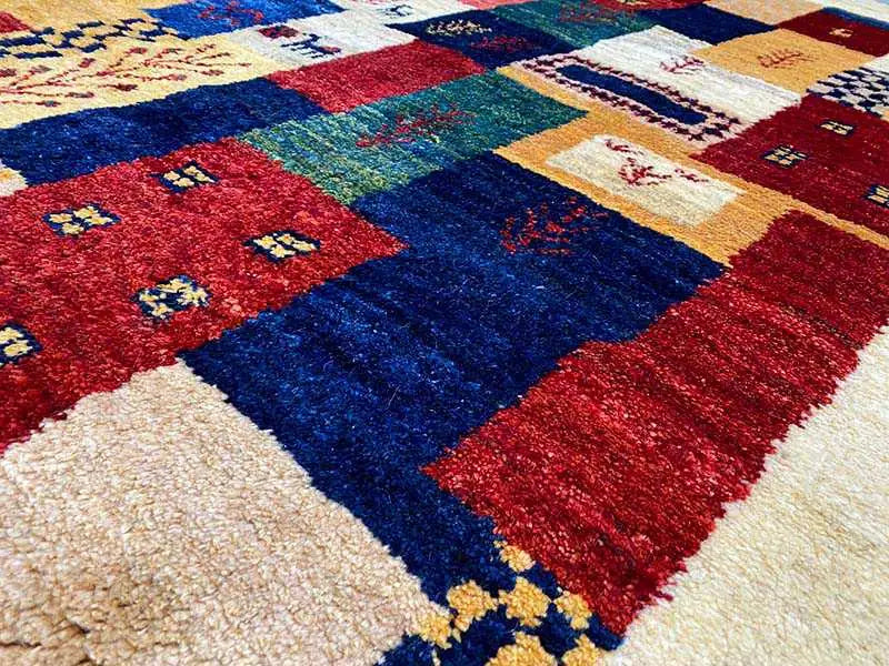 Gabbeh rug detail with dense pile and geometric pattern in red, blue, yellow, and white