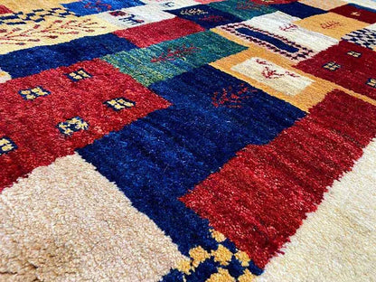 Gabbeh rug detail with dense pile and geometric pattern in red, blue, yellow, and white