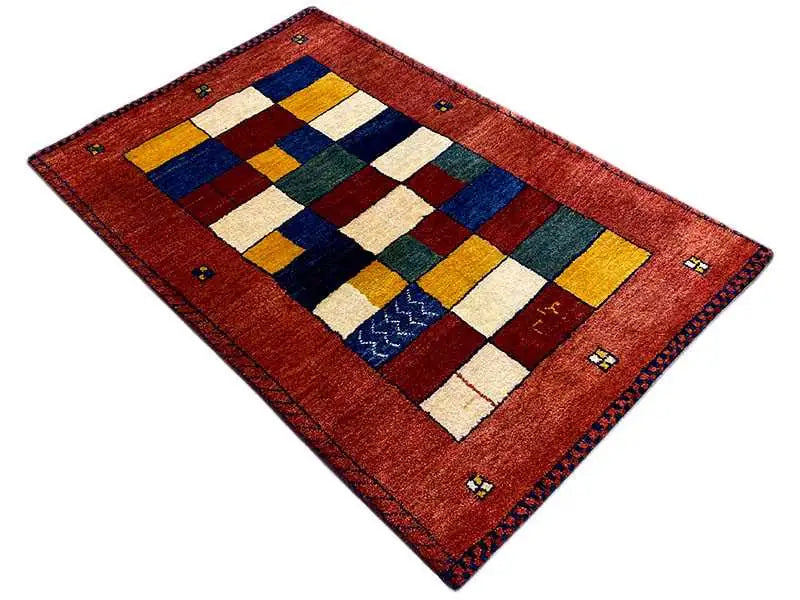Rectangular Gabbeh rug, red patchwork pattern with geometric color blocks