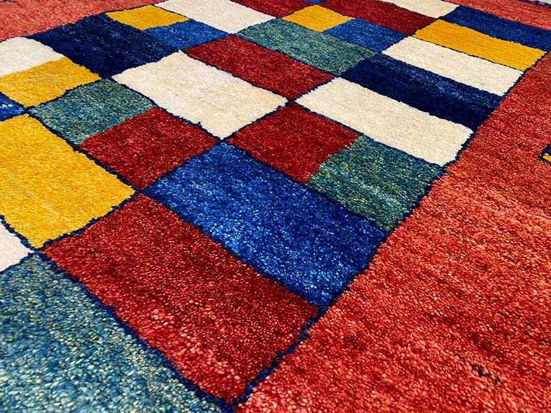Gabbeh rug detail view: colorful patchwork square pattern in yellow, blue, green, red