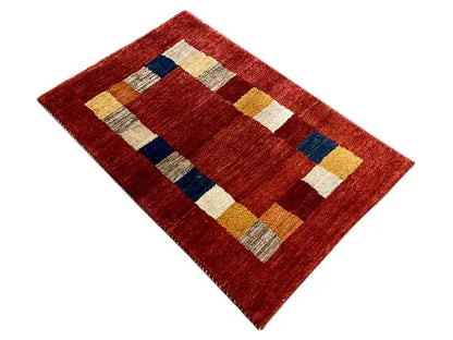 Gabbeh rug: reddish-brown rug with diagonally arranged quadrilaterals in blue, beige, and yellow.
