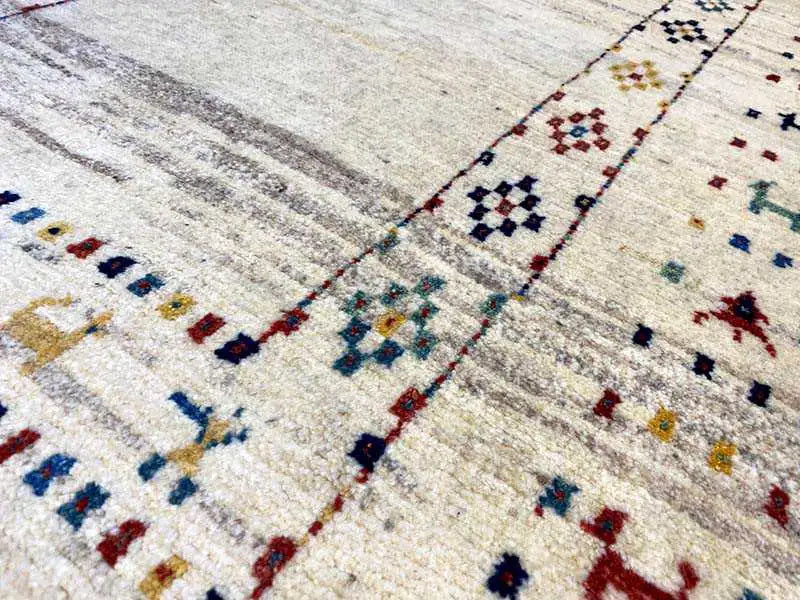 Gabbeh rug detail: geometric ornaments in blue, red, and black on a light background