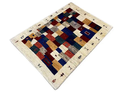 Gabbeh rug with tile-like patchwork and a beige background, accented in blue and red.