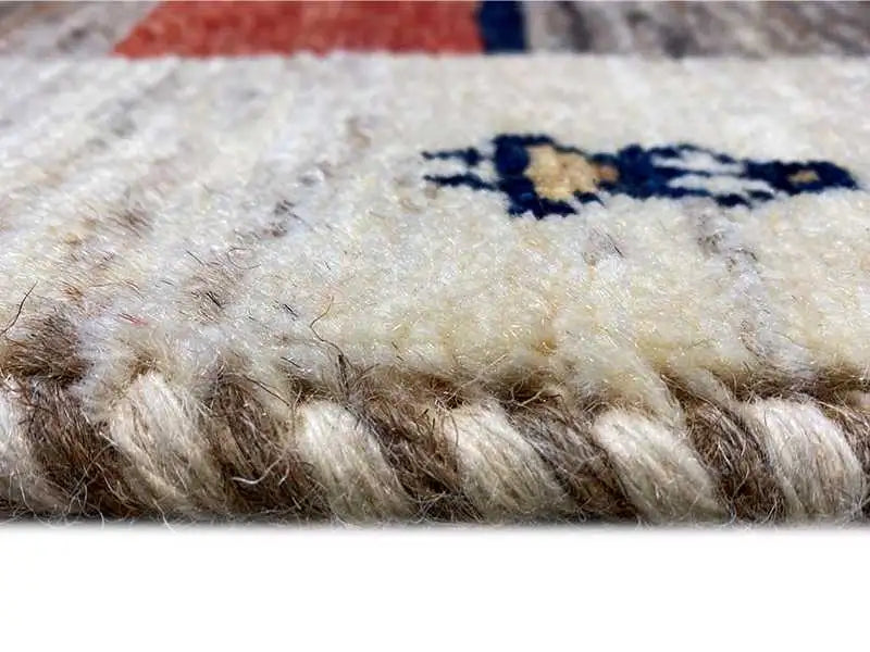 Gabbeh rug pile detail: soft, mottled surface on a beige background, with dark threads.