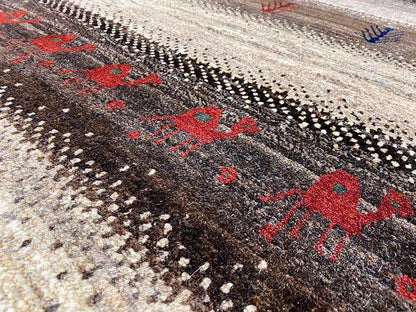 Gabbeh rug close-up: red diamonds, black dot patterns, and a beige background