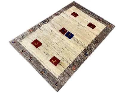 Gabbeh rug in an angled view: beige background, gray border, and red/ blue squares