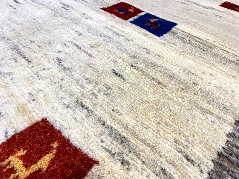 Gabbeh rug detail: light surface with red and blue square accents