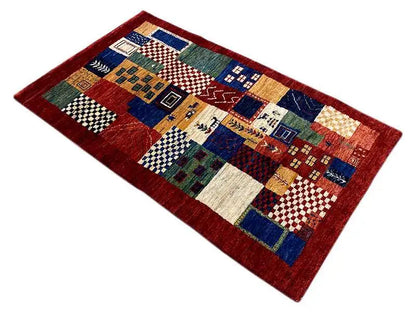 Gabbeh patchwork rug in red with blue, green, and beige, rectangular