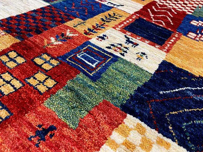 Gabbeh rug detail with geometric patchwork sections in red, blue, green, and beige