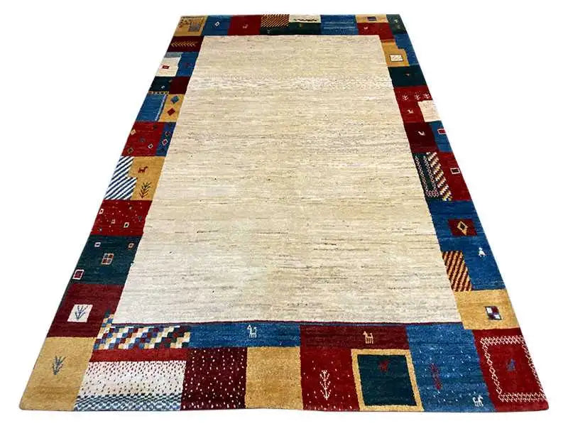 Gabbeh rug 262x177 cm with a wide beige central section and multicolored patchwork border
