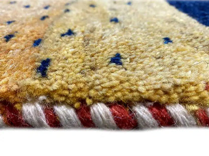 Gabbeh rug detail: yellow pile with blue dots and a red border