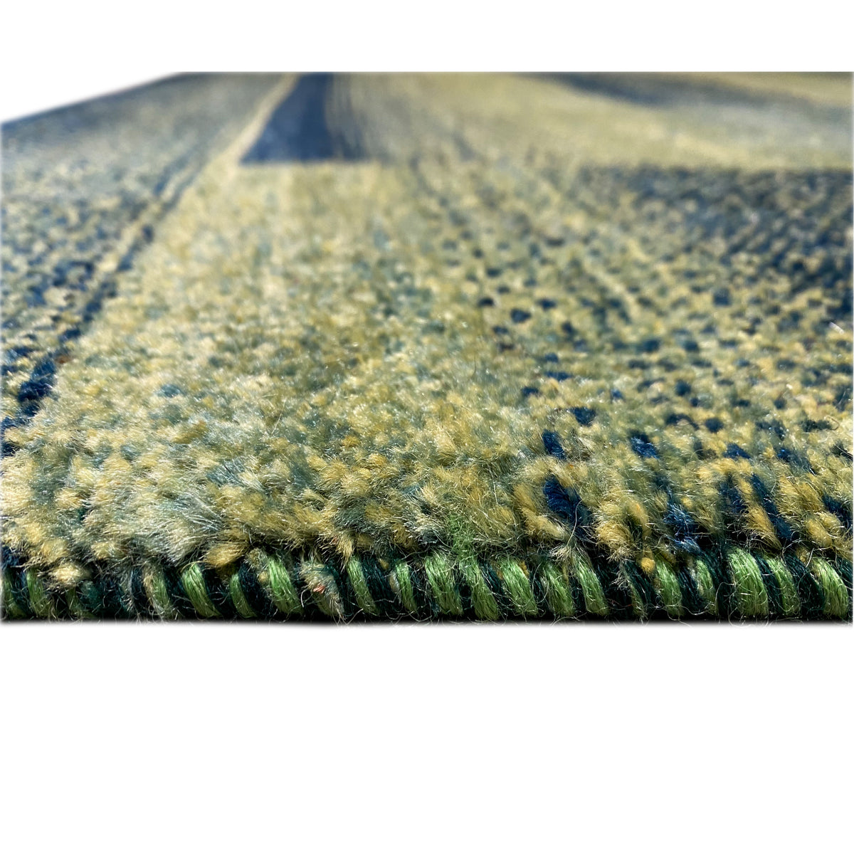 Green gabbeh rug, close-up of the pile surface, mottled texture, with edge.