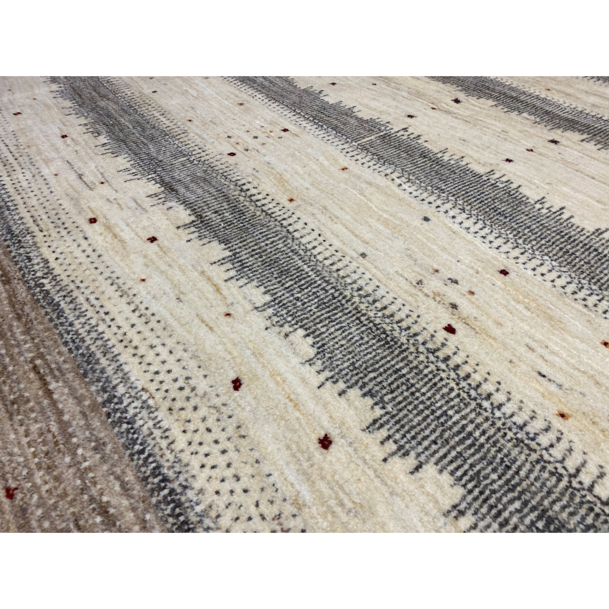 Close-up of a Gabbeh rug: fine texture, striped fabric in beige and gray with dots