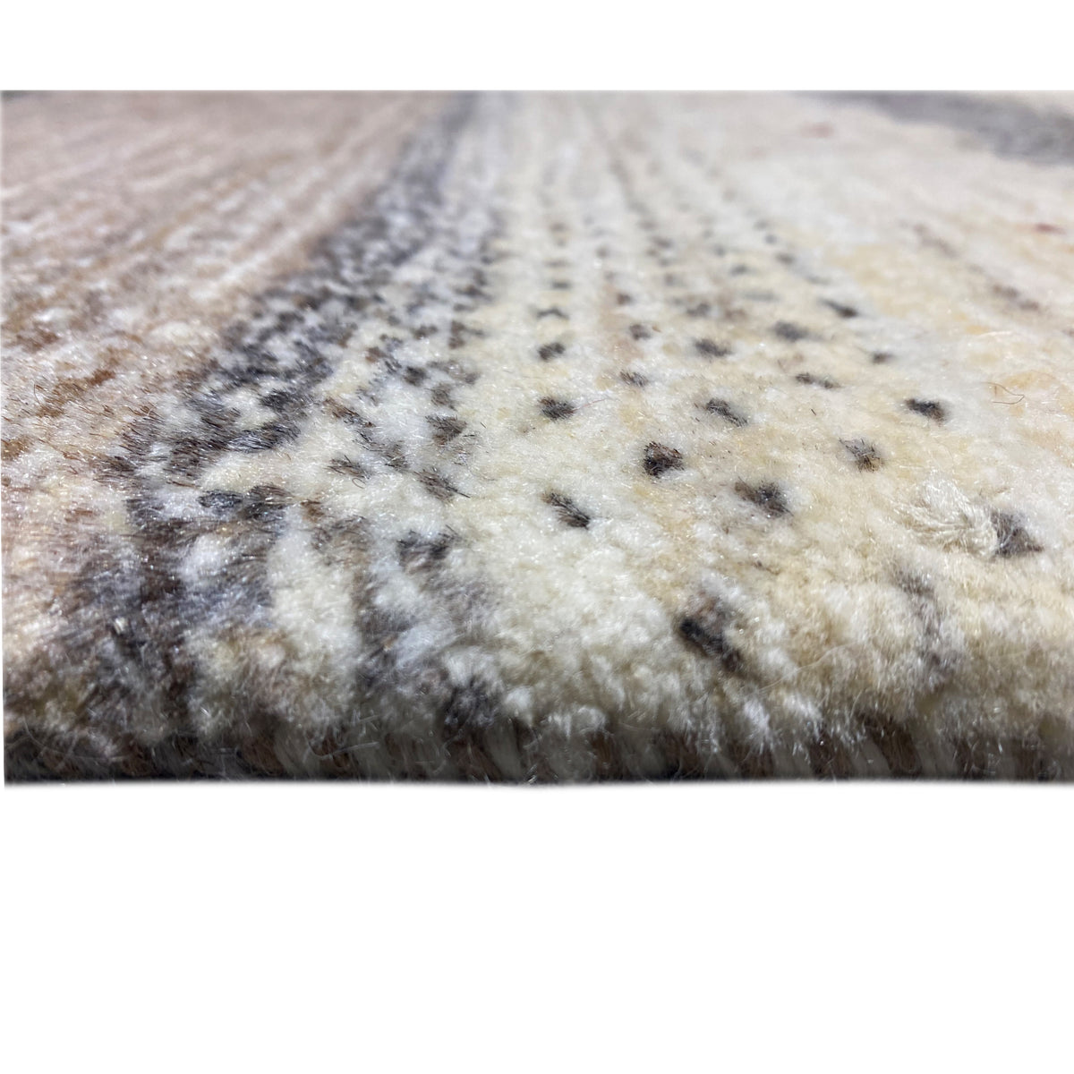 Close-up of a Gabbeh rug with a short pile, a beige-gray pattern, and dark dots