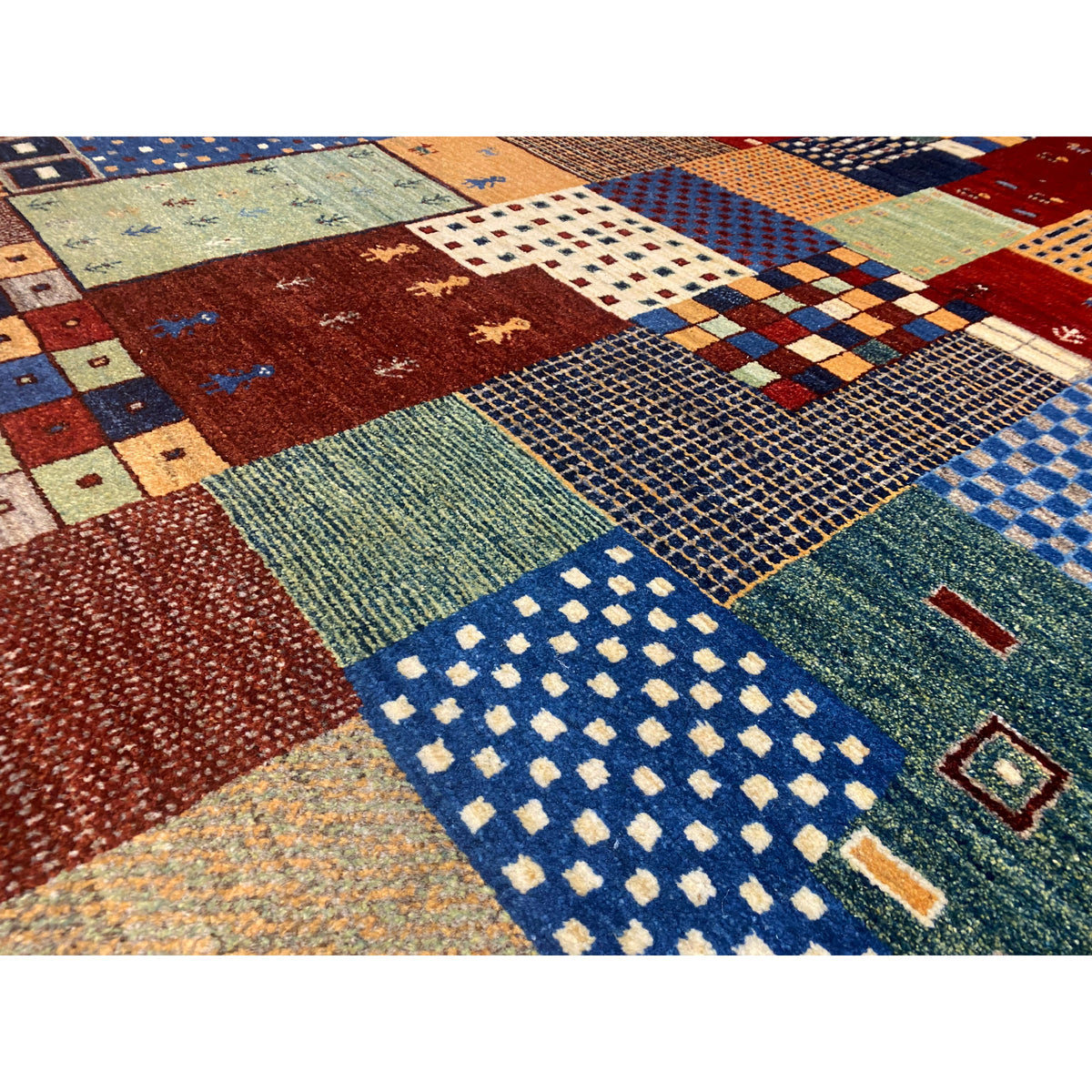 Close-up of a Gabbeh rug: woven patchwork areas with textured pile in blue and red