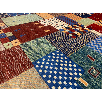 Close-up of a Gabbeh rug: woven patchwork areas with textured pile in blue and red