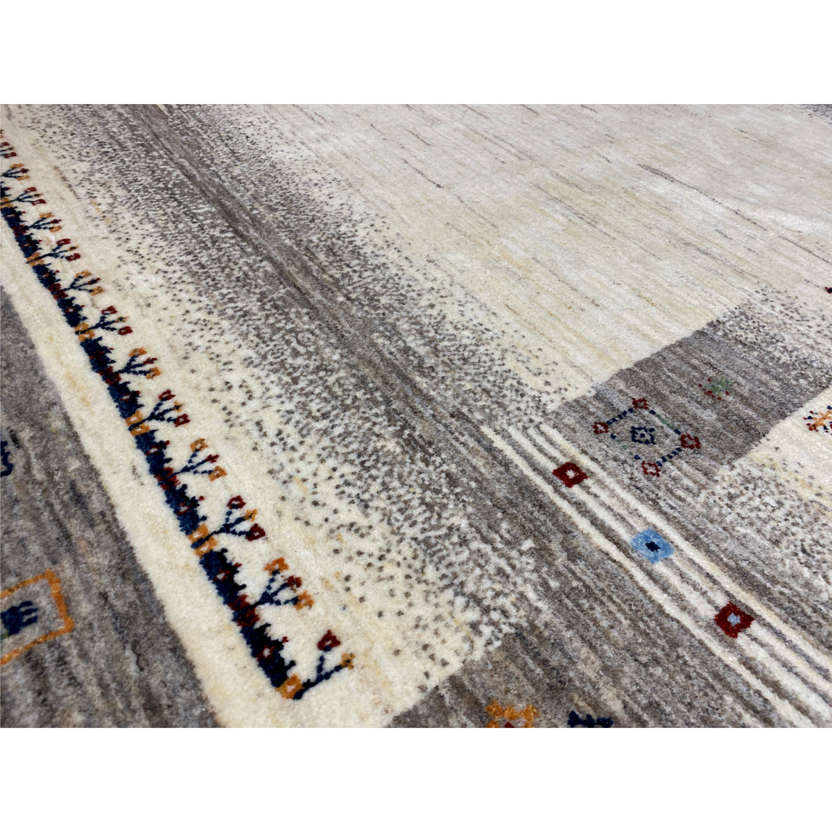 Close-up view of a Gabbeh rug: mottled texture, border with colorful small patterns