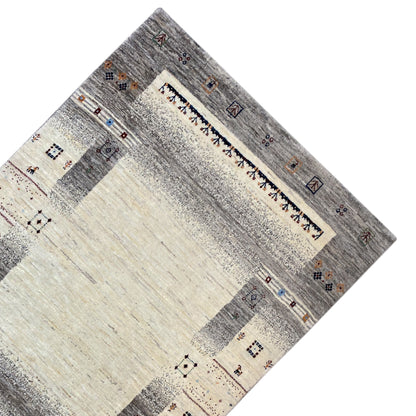 Gabbeh rug in beige/gray, photographed at an angle, with a central stripe and corner motifs