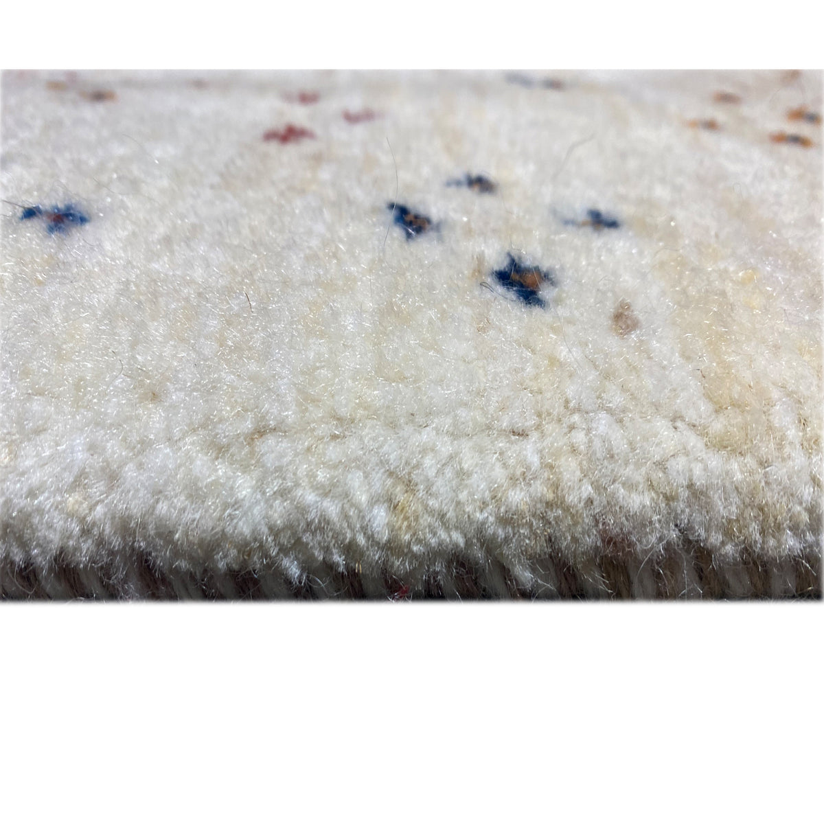 Gabbeh rug detail with pile: beige background and small blue-and-multicolored dot accents