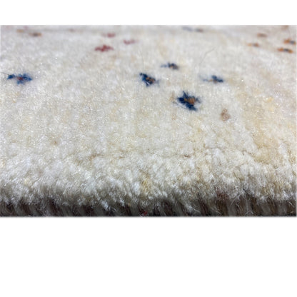 Gabbeh rug detail with pile: beige background and small blue-and-multicolored dot accents