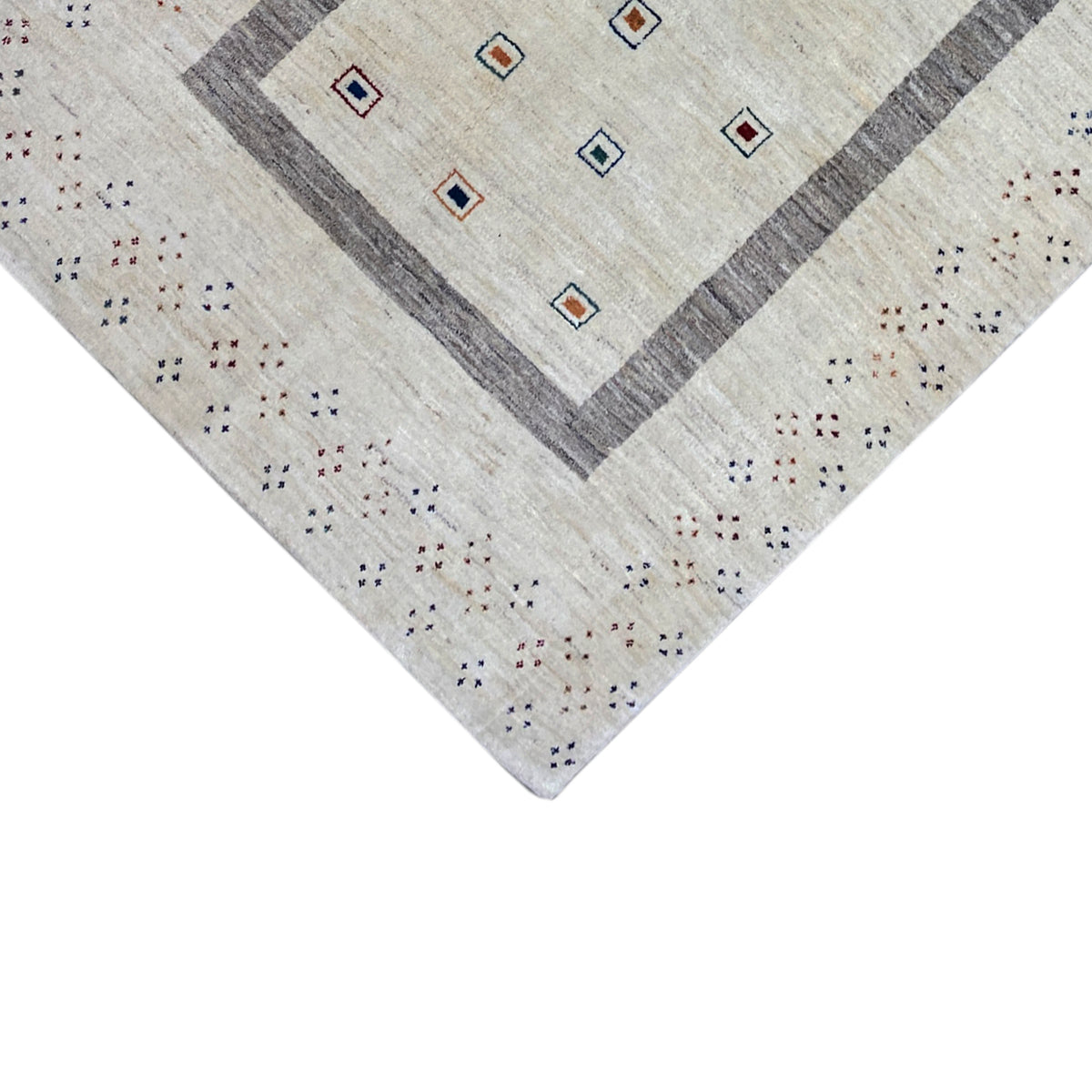 Gabbeh rug corner detail with central diamonds, a beige field, and beige decorative stitching