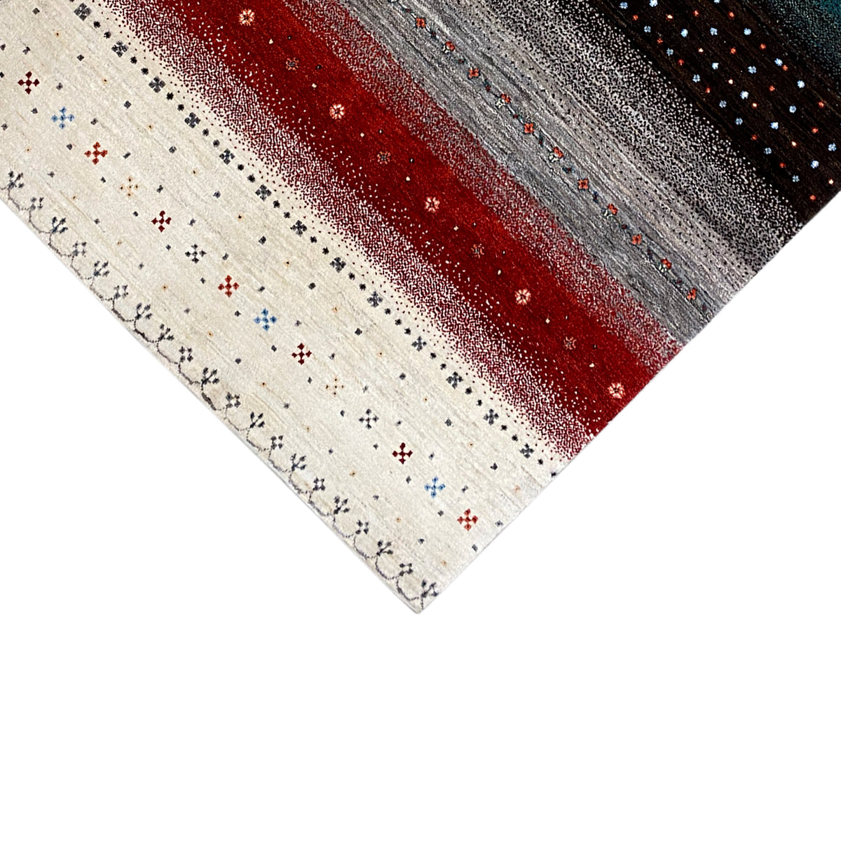 Corner of the Gabbeh rug: cream-colored area with a pattern, with red and gray stripes above it.